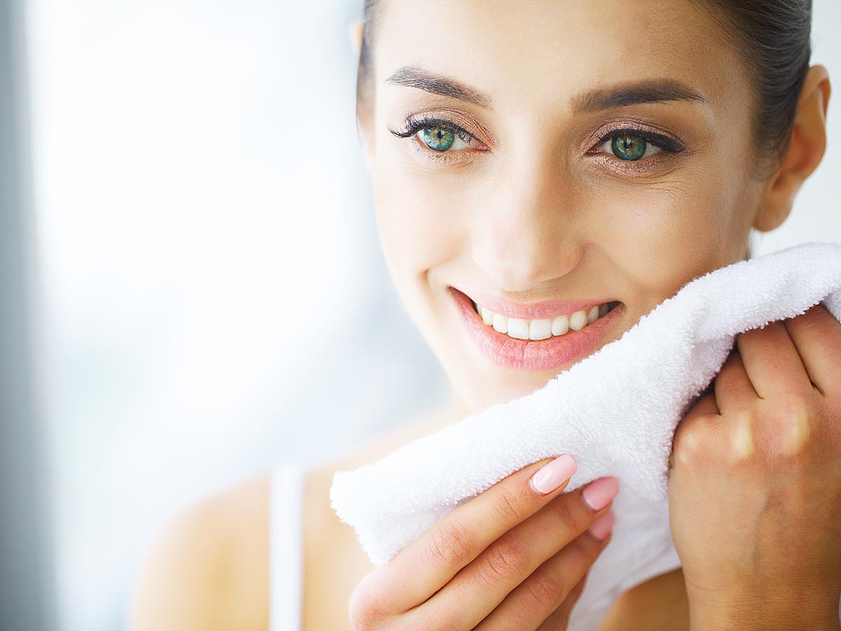 Woman washing her face with a washcloth