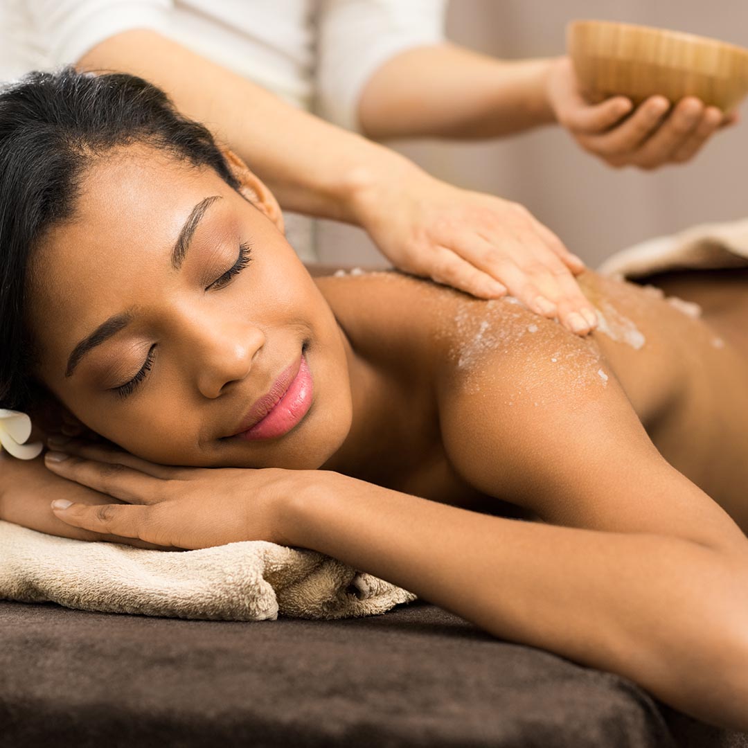 A woman getting her back massaged with a body scrub