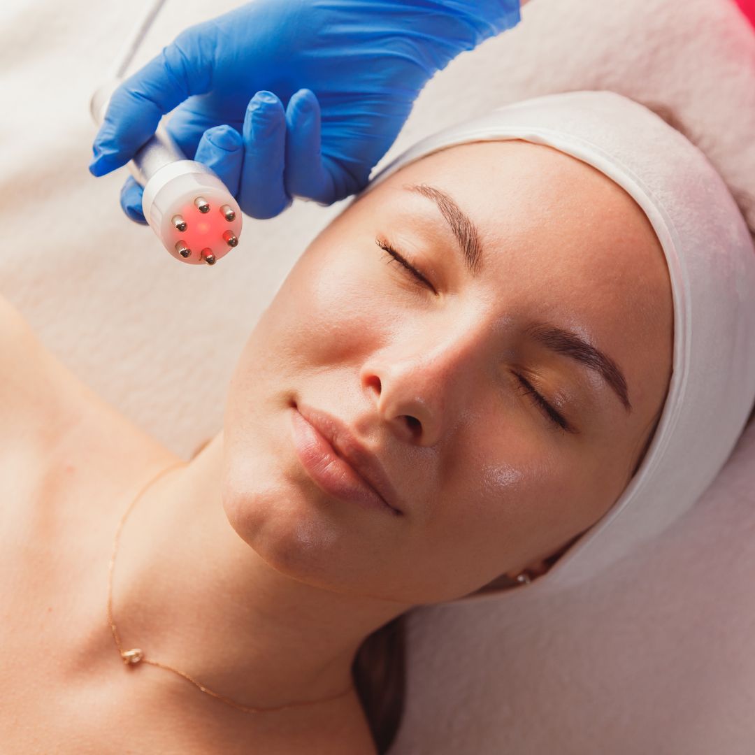 Woman having red light treatment done on face