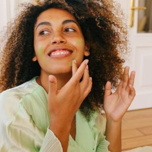 woman smiles spreading skincare on face